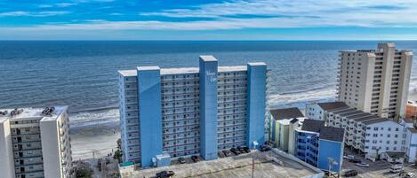 A high-rise hotel with multiple floors, a parking garage, and a view of the ocean.