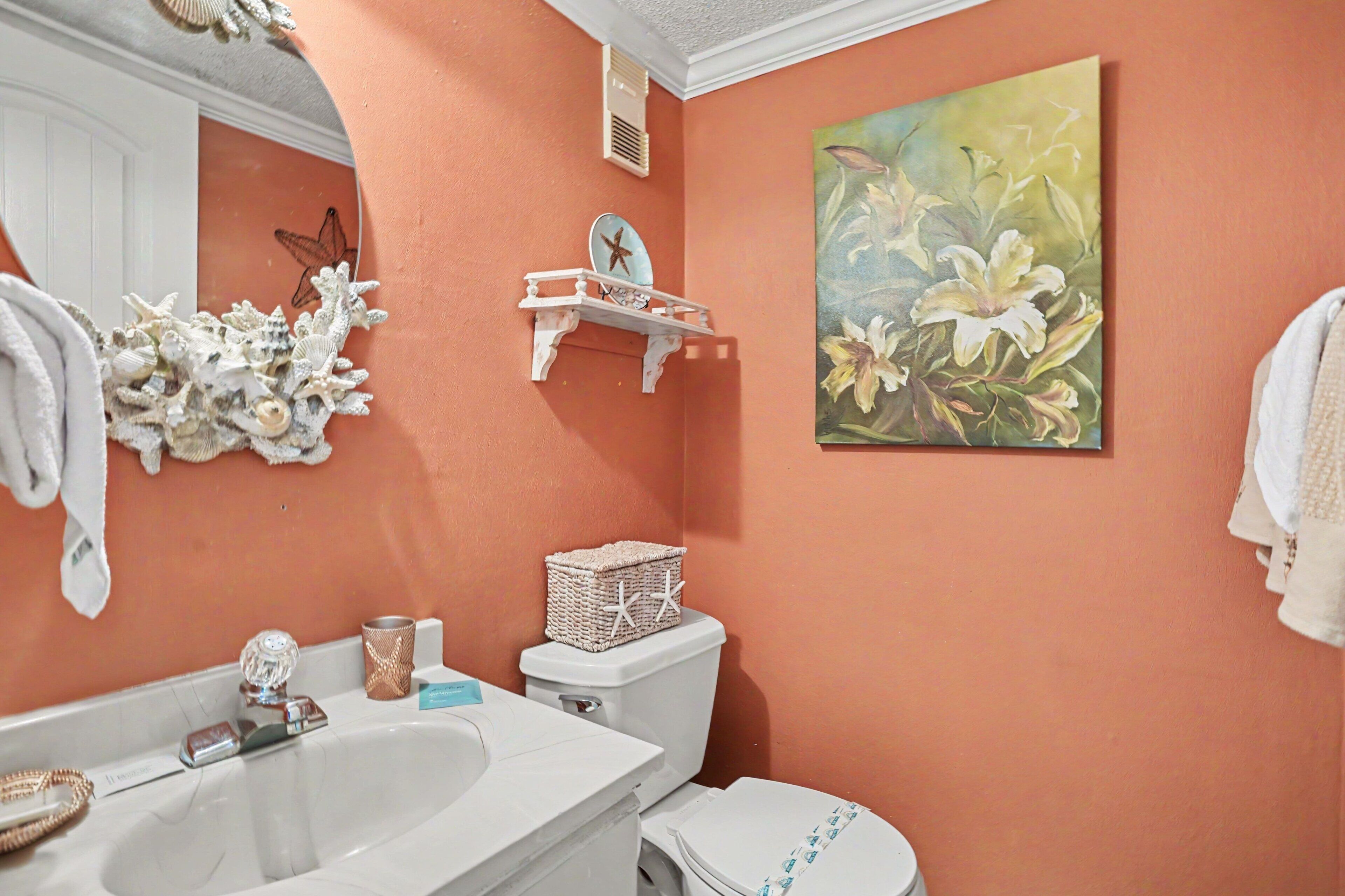 Une salle de bain avec un lavabo blanc, des toilettes et un tableau représentant des fleurs accroché au mur.