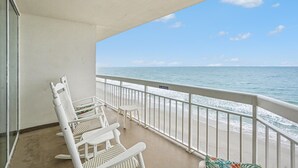 A balcony with white wicker chairs and a small table, overlooking the ocean. - 0801 Waters Edge Resort 3 Bedroom Condo by RedAwning (Murrells Inlet)