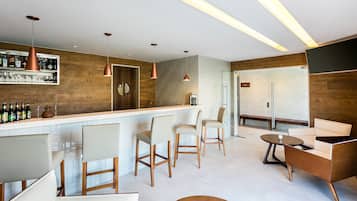 A modern bar area with a wooden accent wall, bar stools, and pendant lighting.