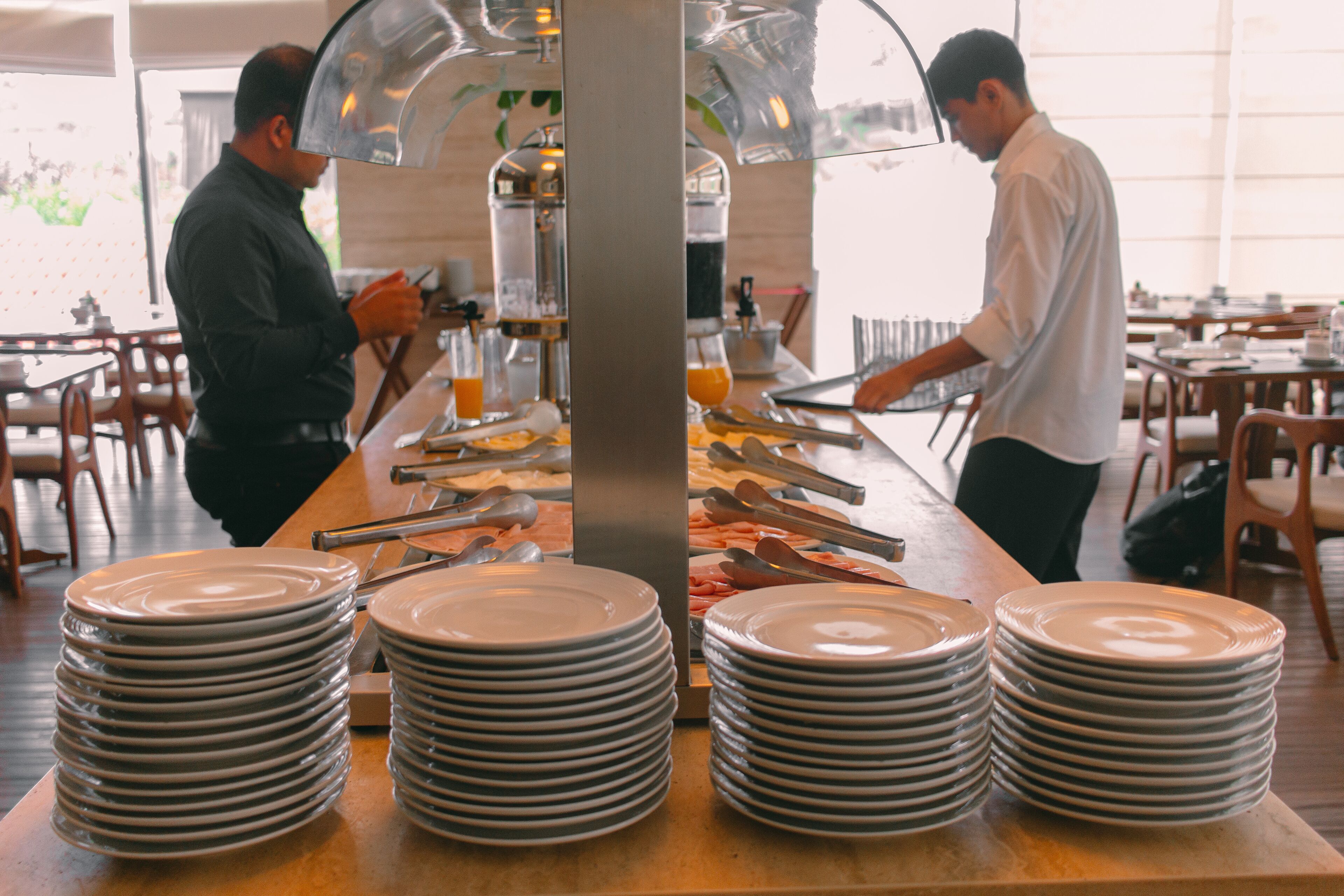 A buffet setup with multiple stacks of plates and serving utensils.