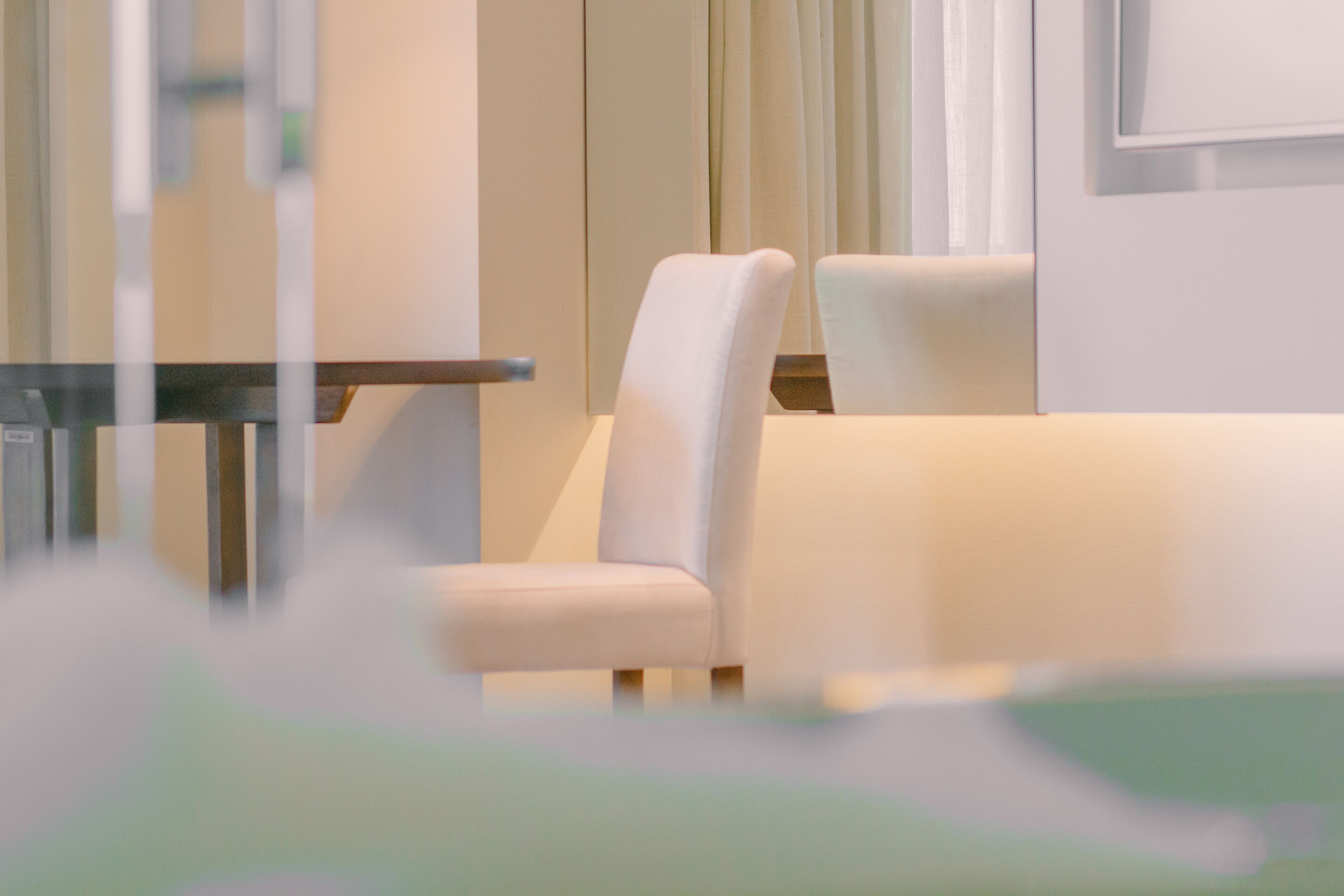 Una habitación de hotel moderna con un sofá, una mesa y un ventanal con cortinas.