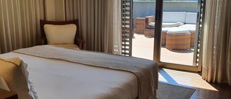 Een hotelkamer met een groot bed, een aan de muur bevestigde televisie en een glazen schuifdeur naar een buiten zitgedeelte.