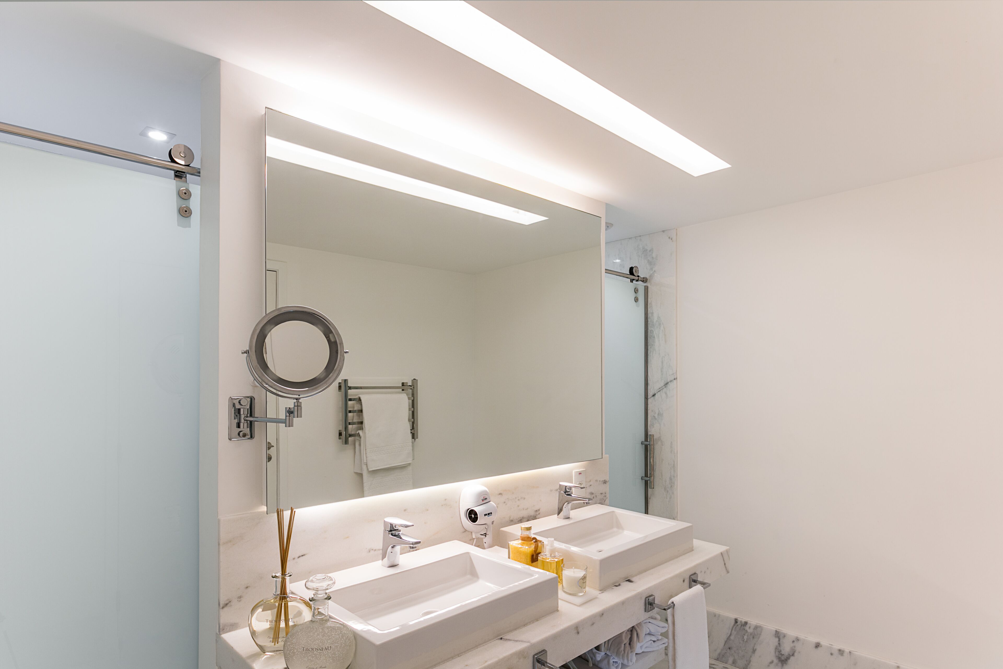 A modern bathroom with two sinks, a large mirror, and a glass shower enclosure.