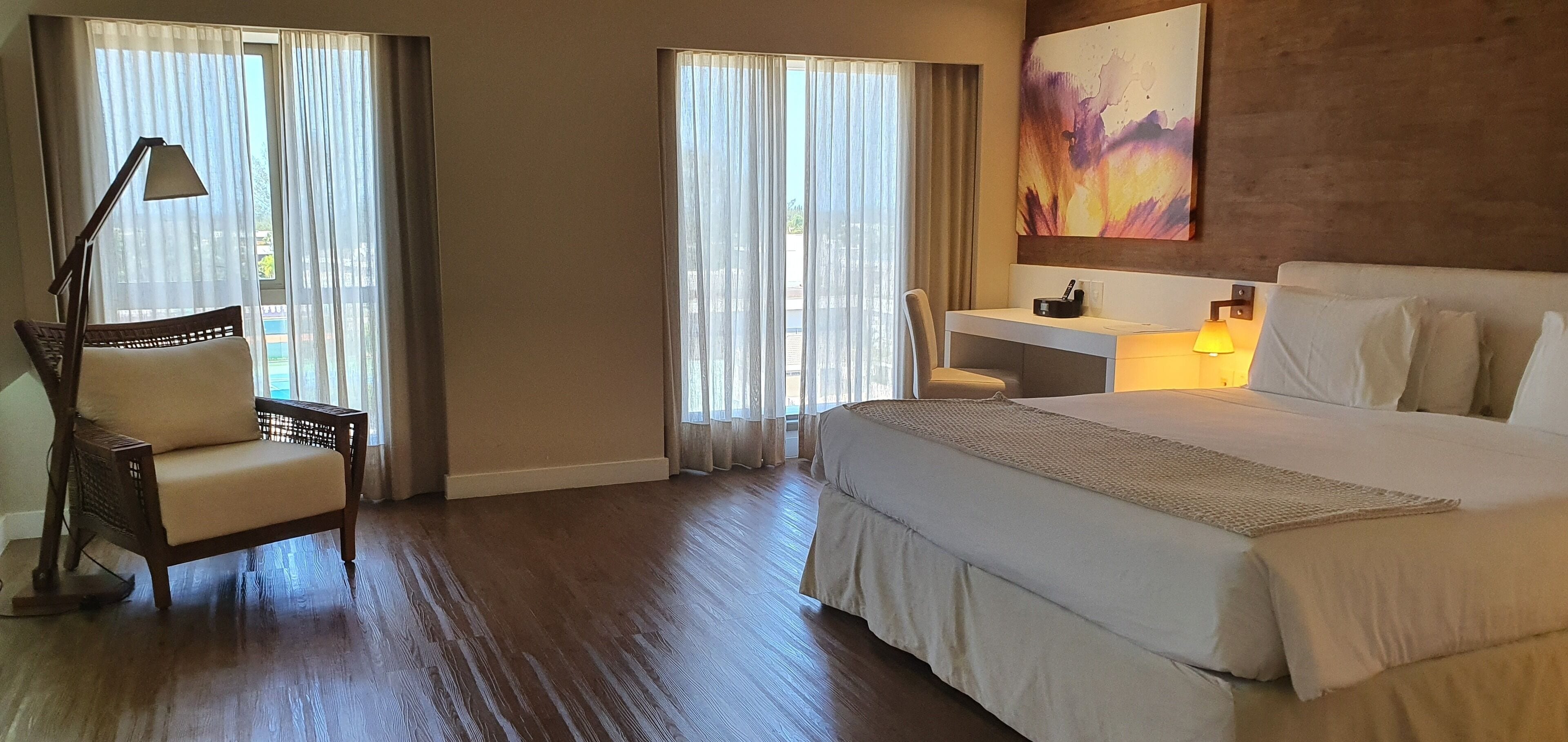 Ein Hotelzimmer mit einem großen Bett, einem Schreibtisch, einem Stuhl und einer Schreibtischlampe.