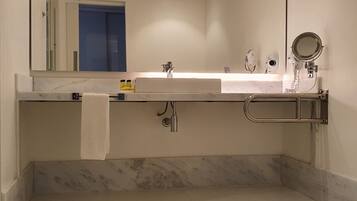 A modern bathroom with a large mirror, two sinks, a towel rack, and a handheld mirror.