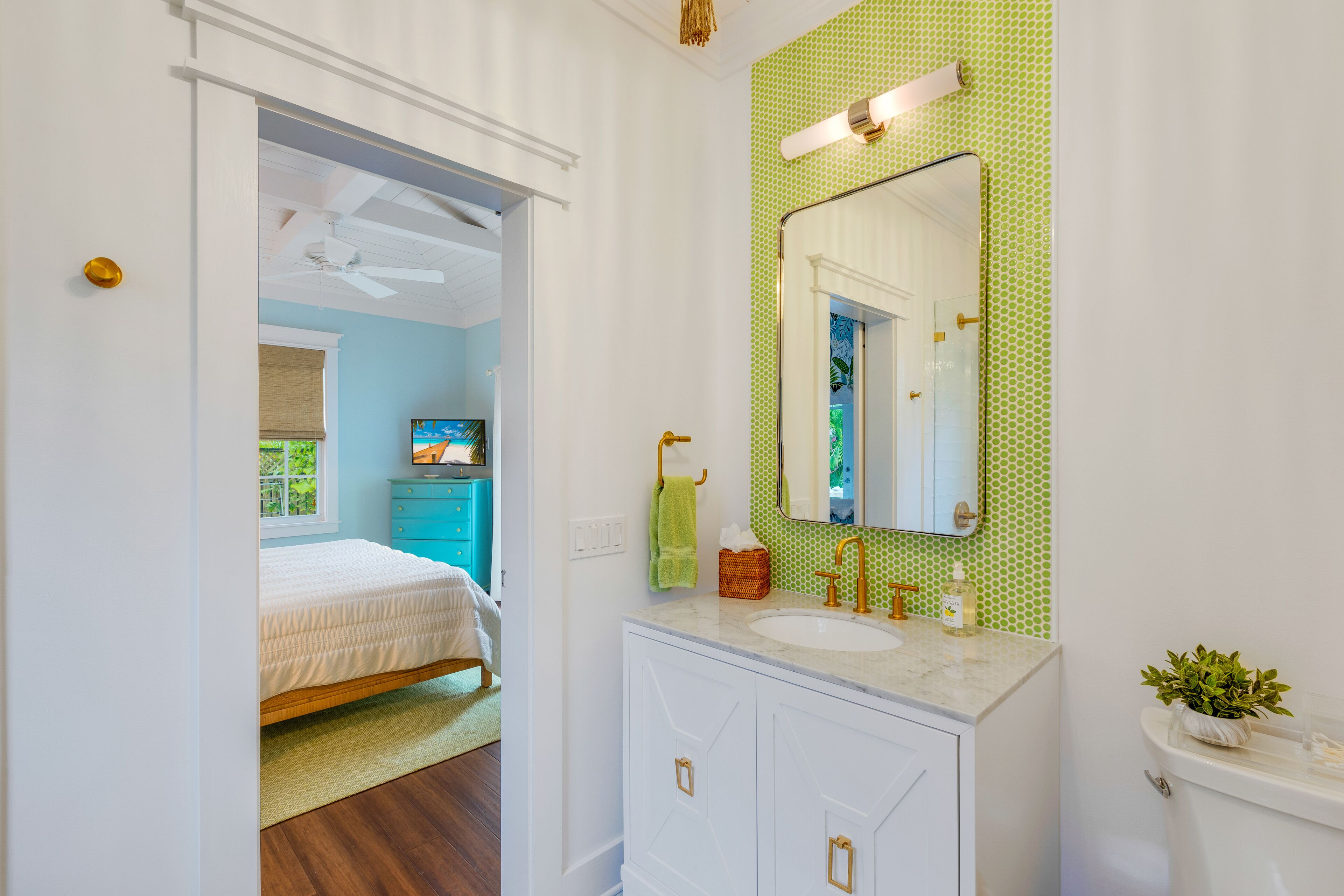 A bedroom with a bed, a bathroom with a sink, mirror, and toilet.