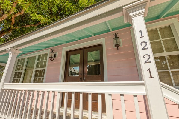 A house with a porch, a wooden door, and a window. - PINEAPPLE BREEZE ~ JUST RENOVATED Home in The Meadows with Pool! (Key West)