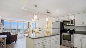 A modern kitchen with white cabinets, stainless steel appliances, and a large island.