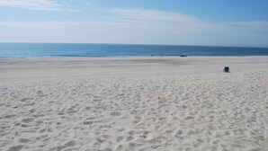 Un'ampia spiaggia sabbiosa con cielo sereno e mare calmo.