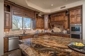 A spacious kitchen with granite countertops, wooden cabinets, and a large island.