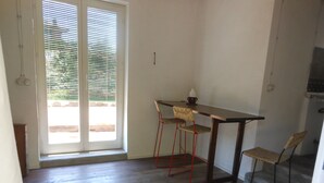 Una cuina petita amb una taula i dues cadires, una porta corredissa de vidre i vistes a l'exterior.