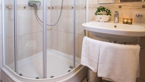 A modern bathroom with a glass-enclosed shower, a sink with a mirror, and a towel rack.