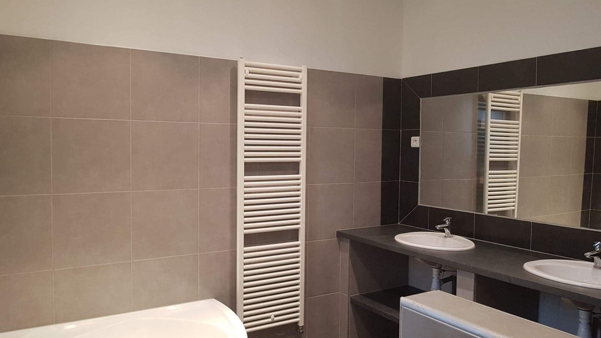 Ein modernes Badezimmer mit einer weißen Badewanne, einem Waschbecken und einem Handtuchhalter.