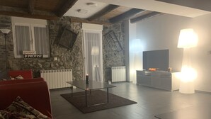 A living room with a stone wall, a fireplace, a TV, and a modern lamp. - House with a different style for families and groups (Biescas)