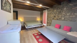 A cozy room with a bed, a sofa, a table, and a stone wall. - House with a different style for families and groups (Biescas)