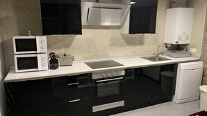 A modern kitchen with black cabinets, a white countertop, a built-in oven, a microwave, a toaster, and a dishwasher. - House with a different style for families and groups (Biescas)