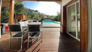 Un espacio al aire libre cubierto con piscina, terraza de madera y mobiliario.