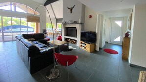 Una sala de estar moderna con un sofá, sillas rojas, un televisor y una chimenea.