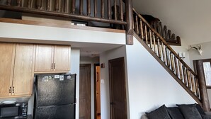 A kitchen with wooden cabinets, a black refrigerator, and a microwave. - Rocky Mountain Cottage (Nordegg)