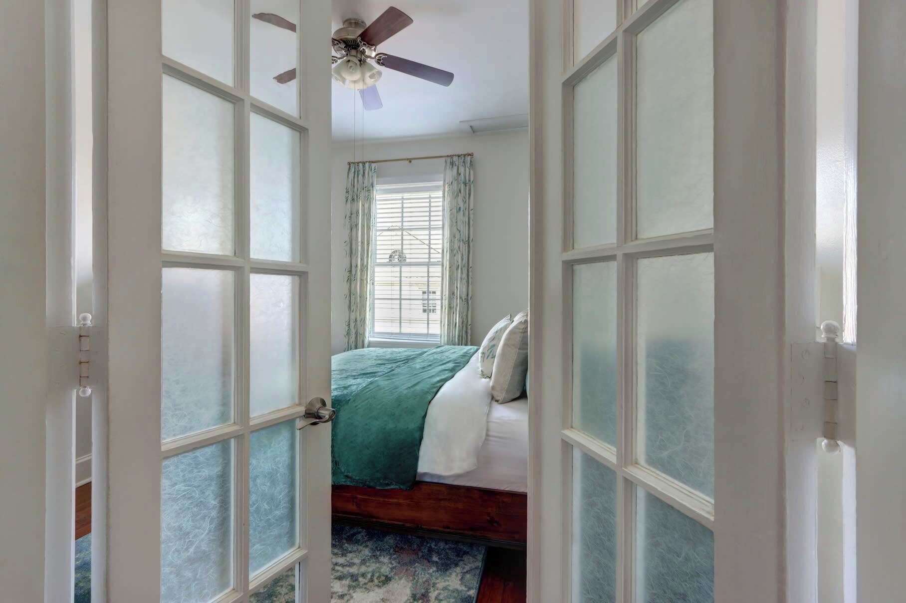 A bedroom with a bed, a ceiling fan, and a window with curtains.