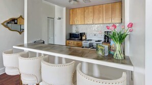 Una cocina con armarios de madera, una encimera blanca, un microondas, una estufa y un jarrón con flores.