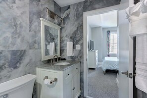 Une salle de bain avec un mur en marbre, un lavabo, un miroir et des toilettes.