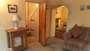 En hyggelig stue med en stribet sofa, et træsidebord med en lampe og en dør, der fører til et andet rum.