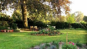 A garden with a lawn, flower beds, and a wooden bench. - HOUSE TOURNEUR - Beautiful apartment with fireplace (Lippetal)