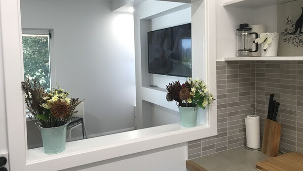 A kitchen with a window, a sink, a countertop, and a cutting board.