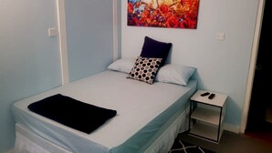 A bedroom with a bed, pillows, a nightstand, and a painting on the wall.