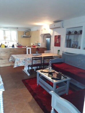 A compact living space with a dining area, kitchen, and a red sofa. - Villa LARIBI seaside in Nabeul. (nabeul)
