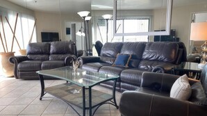 A modern living room with leather sofas, a glass coffee table, and a large mirror. - See The Sea 2-Ocean Front, Dining on Patio, 2 bd! (San Diego)