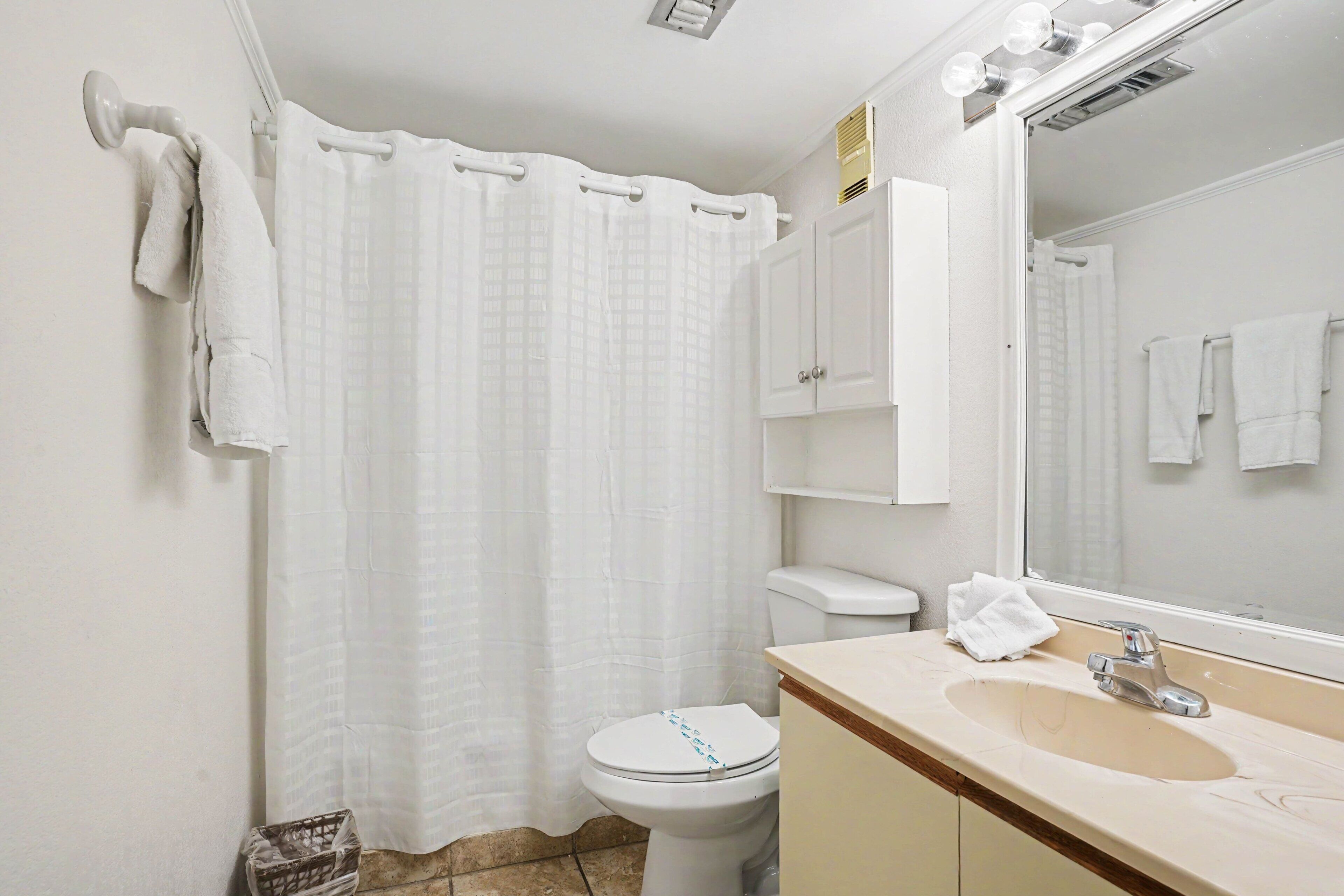 Ein Badezimmer mit Toilette, Waschbecken, Spiegel und Duschvorhang.