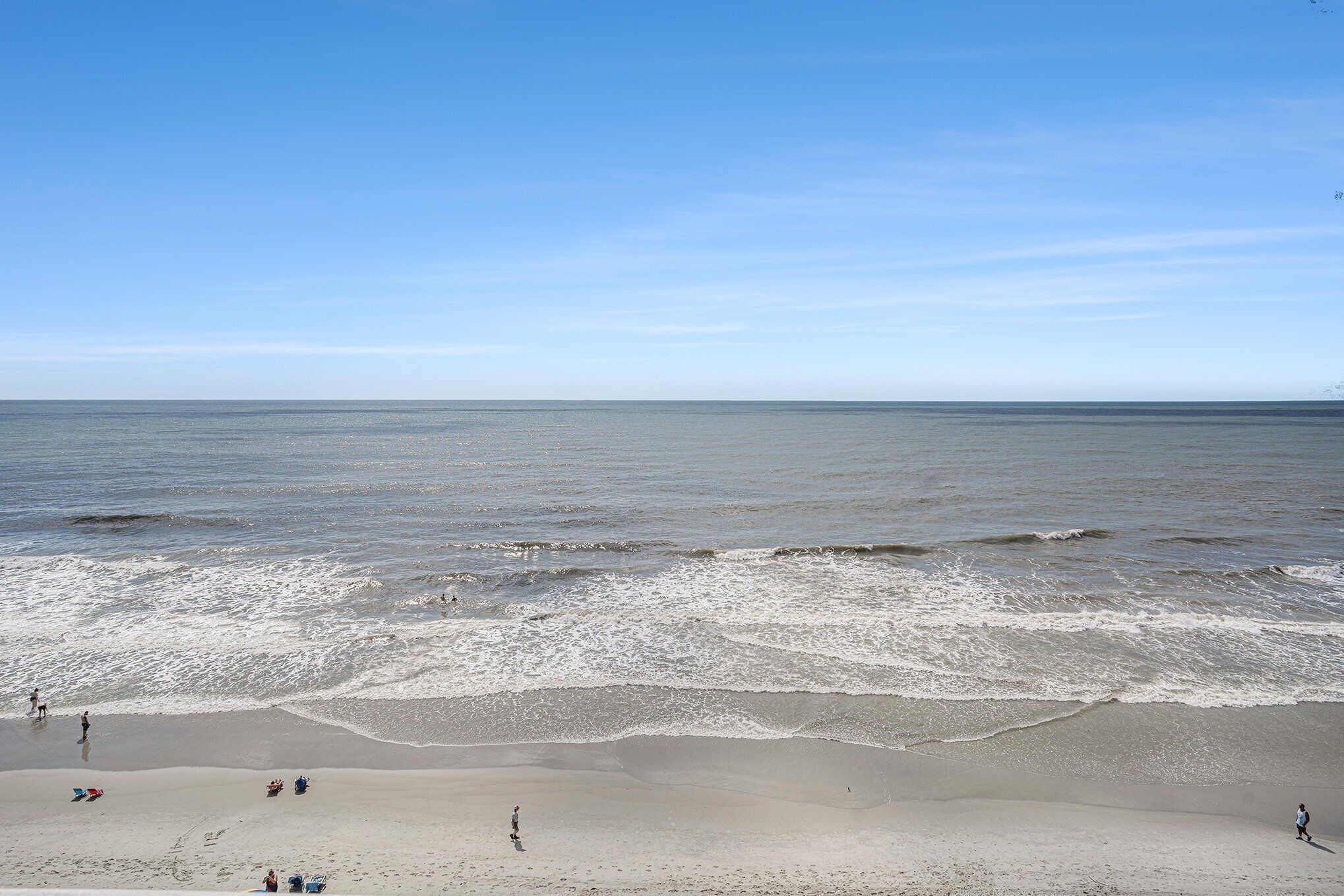 A beach with a wide sandy area and gentle waves.