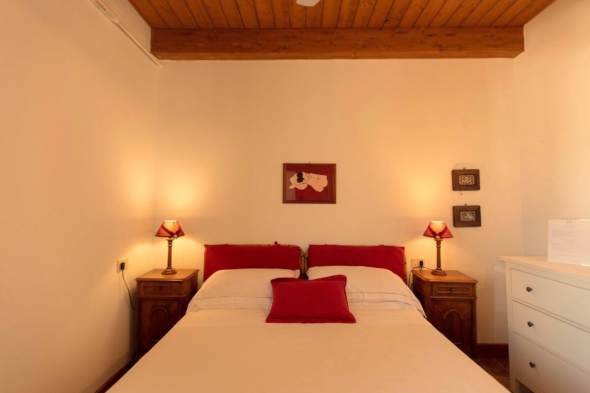 Une chambre à coucher avec un lit, deux tables de chevet avec des lampes, une commode et un plafond en bois.