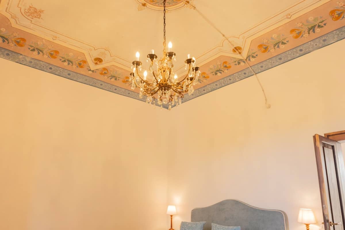 Une chambre à coucher avec un lit, deux tables de chevet, un lustre et une porte.