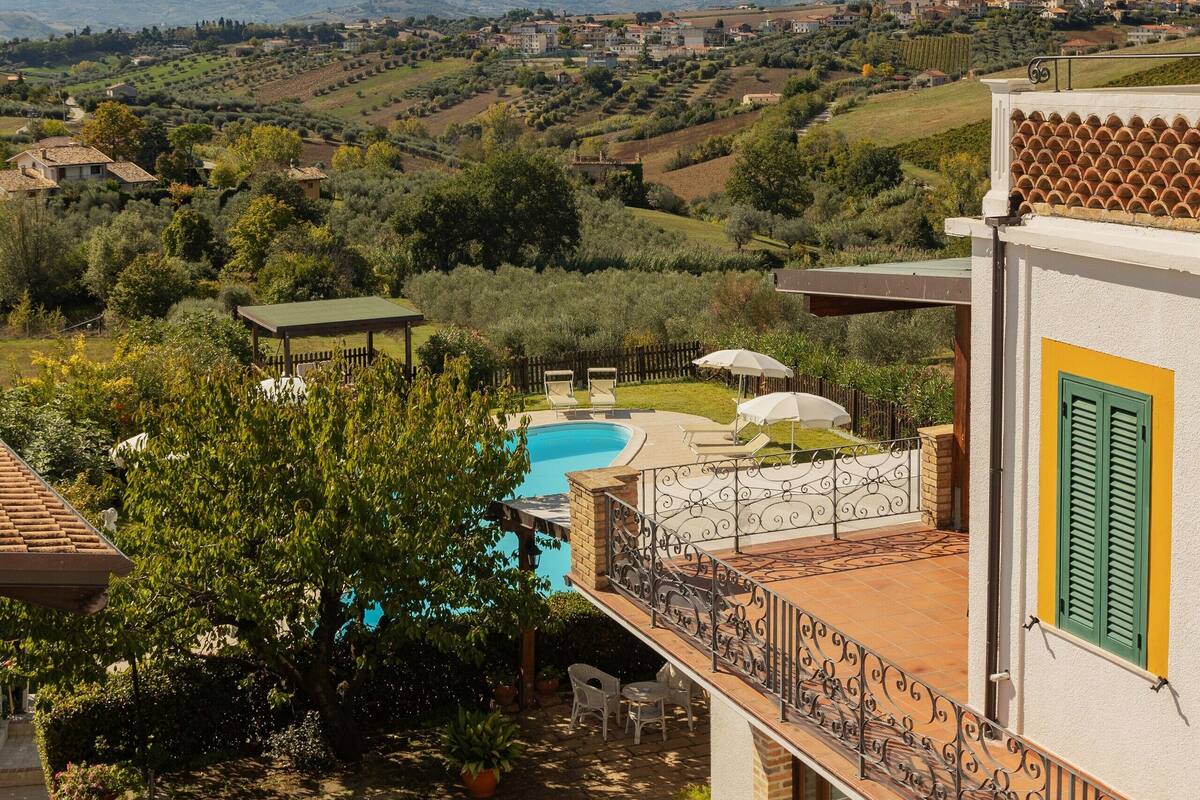 Une villa avec piscine, offrant une vue sur la campagne et sur les montagnes au loin.