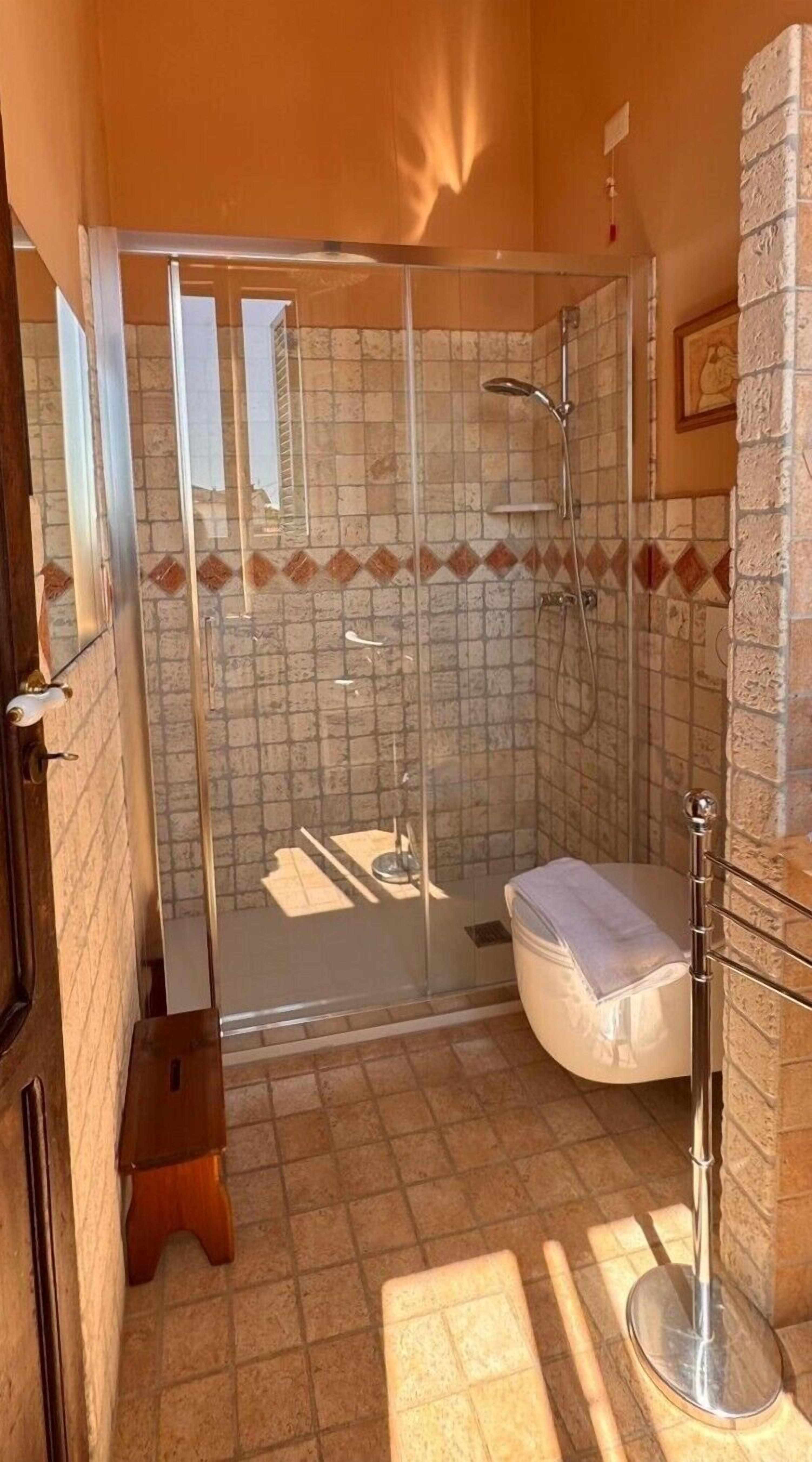 A bathroom with a glass-enclosed shower, a toilet, and a sink.