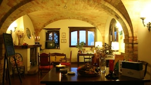 Une pièce chaleureuse avec un plafond en briques, une cheminée, une table à manger et une fenêtre donnant sur un beau paysage.