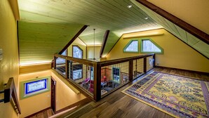 A spacious attic room with wooden beams, a large window, and a colorful rug. - Handicap Accessible cottage at Desoto Falls Mentone, AL  Central Time Zone (Mentone)