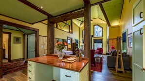 A spacious kitchen with wooden beams, a central island with a vase, and a dining area with a red chair and table. - Handicap Accessible cottage at Desoto Falls Mentone, AL  Central Time Zone (Mentone)