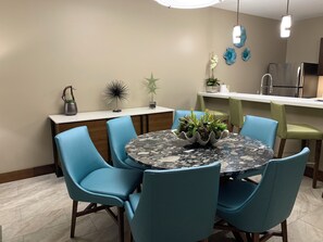 A modern kitchen with a round dining table, blue chairs, and a decorative plant centerpiece.
