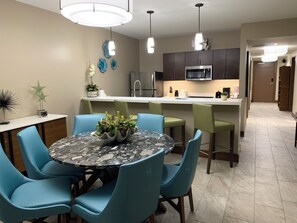 A modern kitchen with a central island, bar stools, and a dining table with chairs. - Spacious 1800 Sq Ft Ocean View Condo (Oyster Pond)
