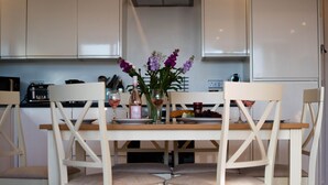 A modern kitchen with white cabinetry, a wooden dining table, and four chairs. - 3 Bedroom Beachside Property with Glass Pod! (Praa Sands)
