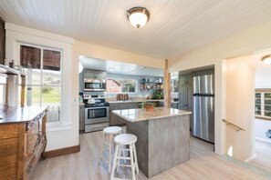 A modern kitchen with a central island, stainless steel appliances, and a view to the outdoors. - HISTORIC FARMHOUSE ON 400 ACRE RANCH (San Luis Obispo)