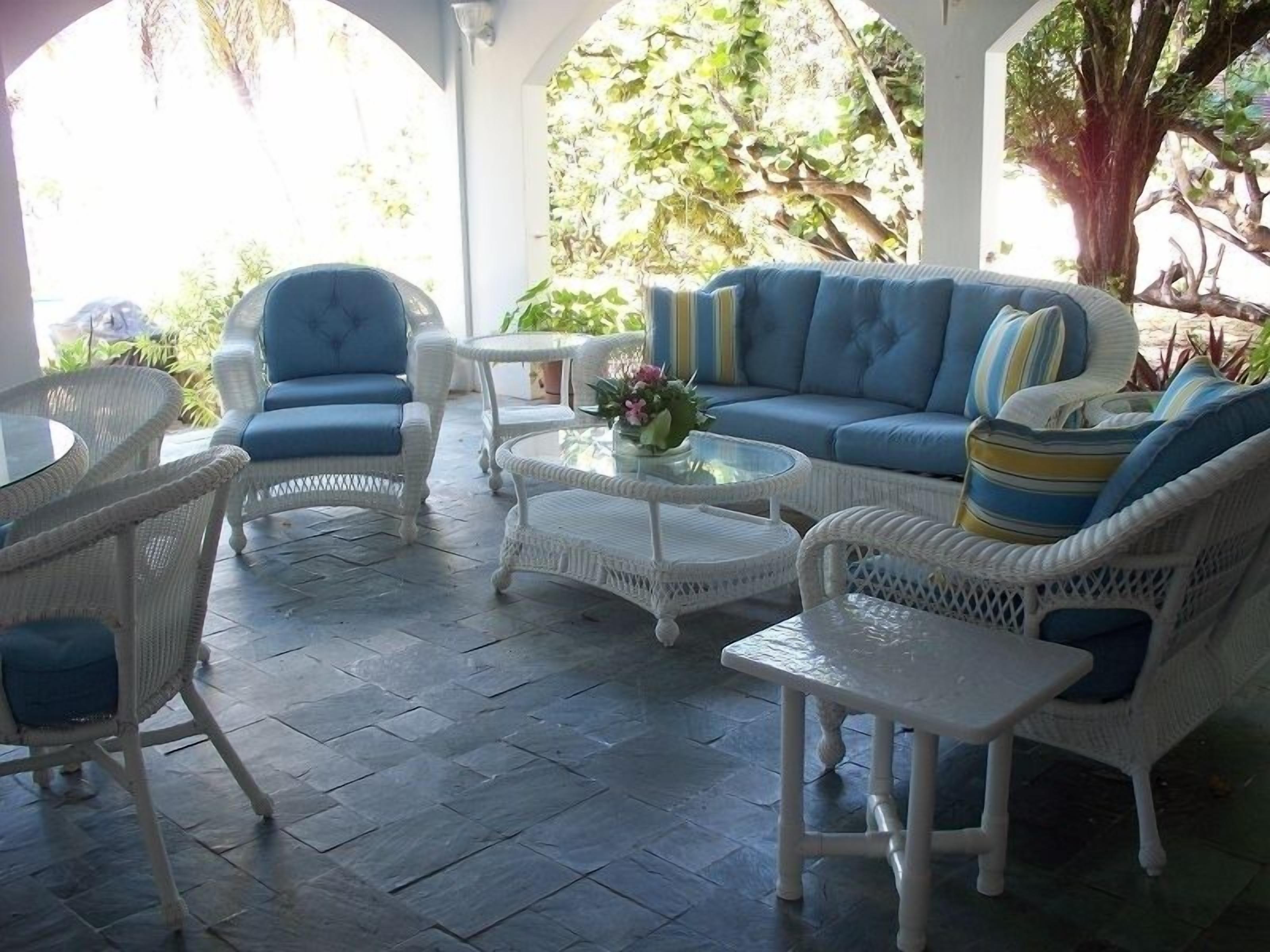 A covered outdoor seating area with wicker furniture, a sofa, and a coffee table.