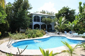 A swimming pool with lounge chairs and a building with arched windows in the background.