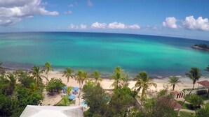 Une plage aux eaux turquoise et limpides, bordée de palmiers et agrémentée de quelques parasols.