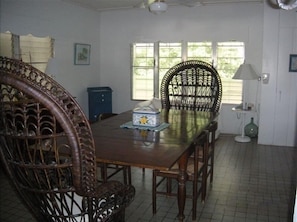 A dining room with a wooden table and chairs, a blue cabinet, and a window with blinds.